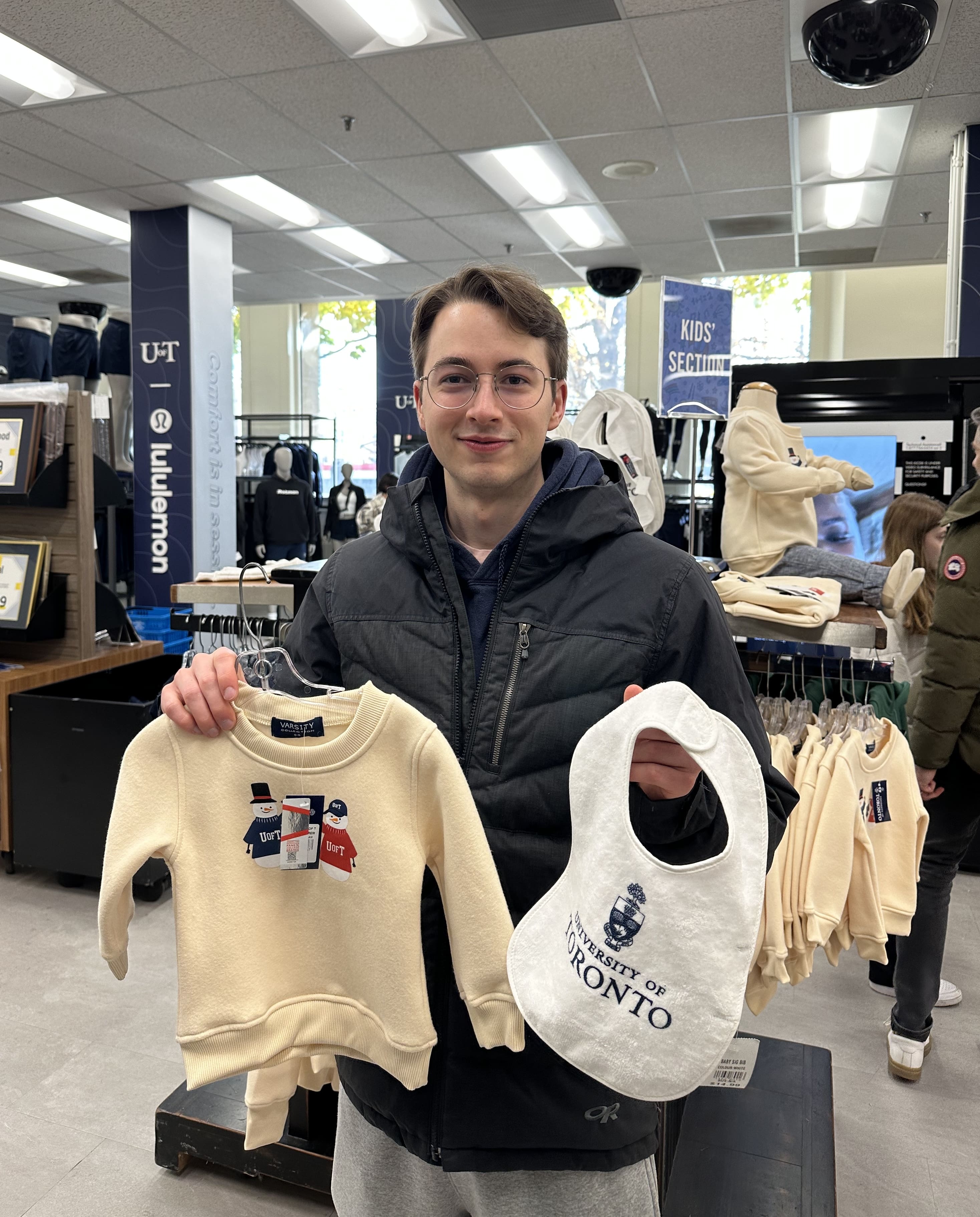 Jonah holding up a sweater and a bib